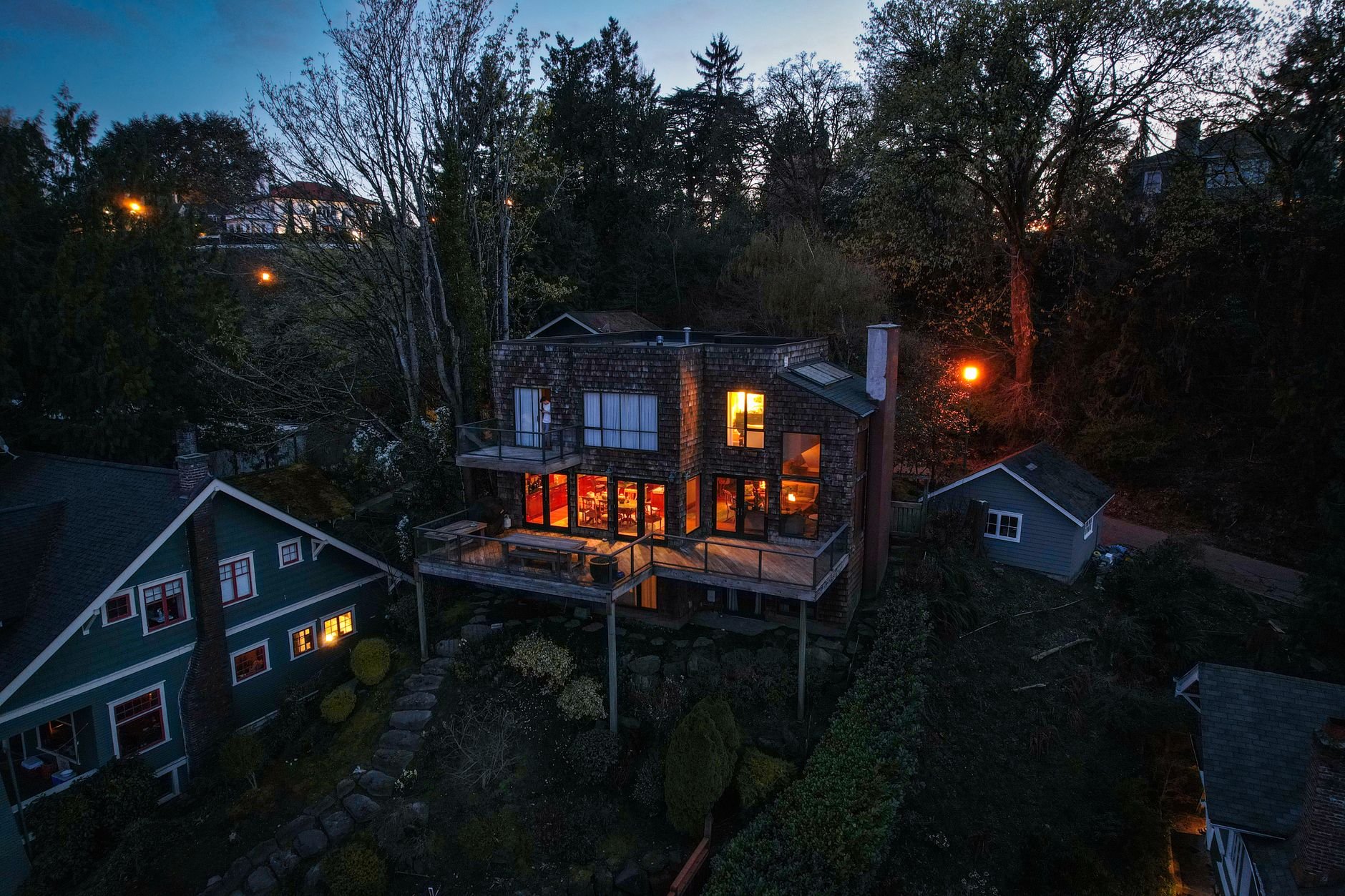 Aerial view of illuminated homes in a lush Pacific Northwest neighborhood at twilight.